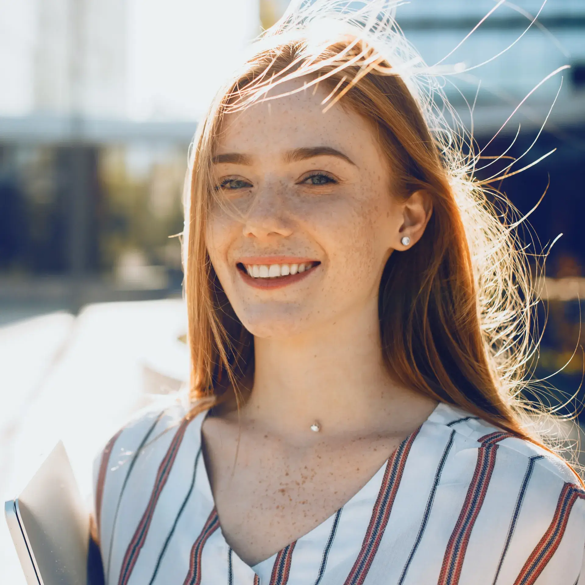 A woman is smiling and holding a folder.