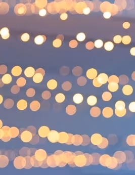 Blurred background of warm round bokeh lights in soft yellow and orange hues.