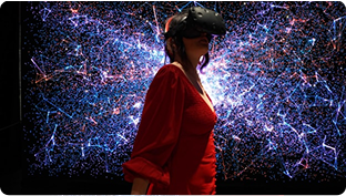 Person wearing a virtual reality headset in front of a colorful digital network visualization.