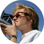 A portrait of a man using a polaroid camera. He is wearing sunglasses