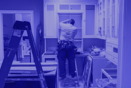 An image of a man repairing cabinets in an under construction kitchen. The entire image is made of shades of purple