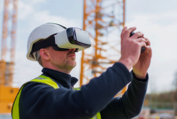 An image of a man in construction gear on a commercial construction project. He is using a VR headset and reaching out