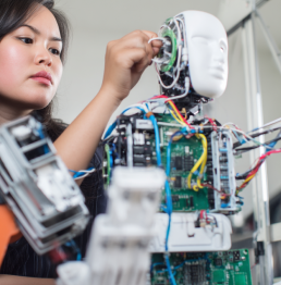 An image of a woman working on a humanoid robot