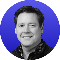 Headshot of a smiling man with dark hair wearing a dark patterned shirt against a blue circular background.