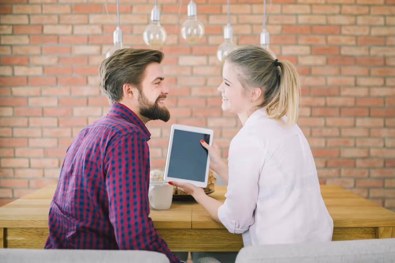 Happy customers sharing a positive review on a tablet, reflecting emotional brand loyalty and trust