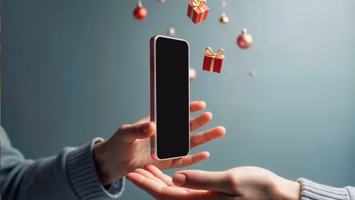 A smartphone floating between two hands with digital gift boxes around it, symbolizing mobile-based customer loyalty rewards.