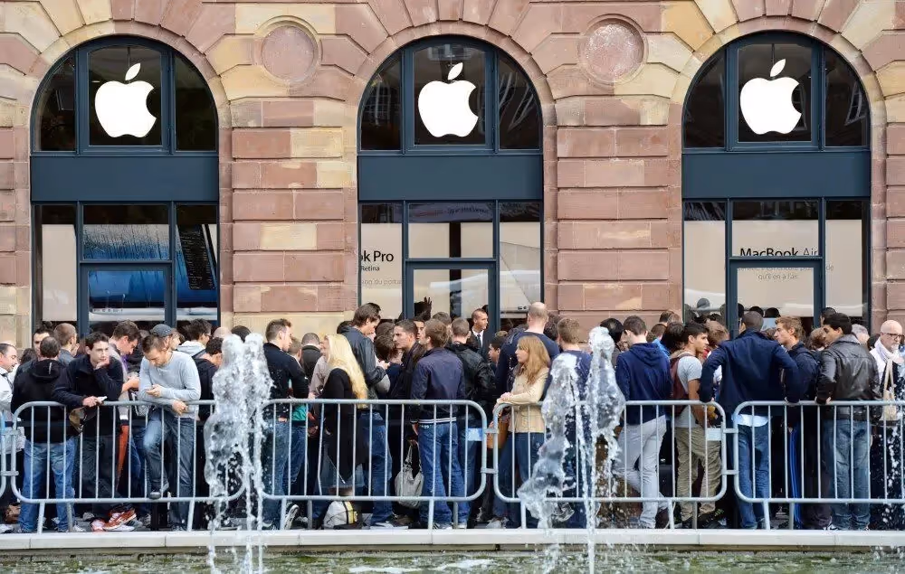 Crowd of people queuing outside an Apple Store, highlighting brand loyalty and high customer demand