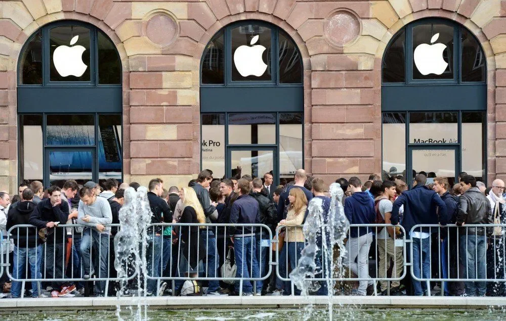 Crowd of people queuing outside an Apple Store, highlighting brand loyalty and high customer demand