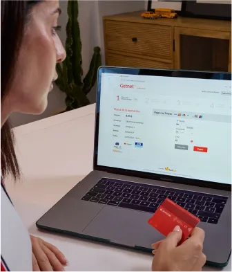 Persona pagando en un comercio online desde un portatil con una tarjeta de crédito