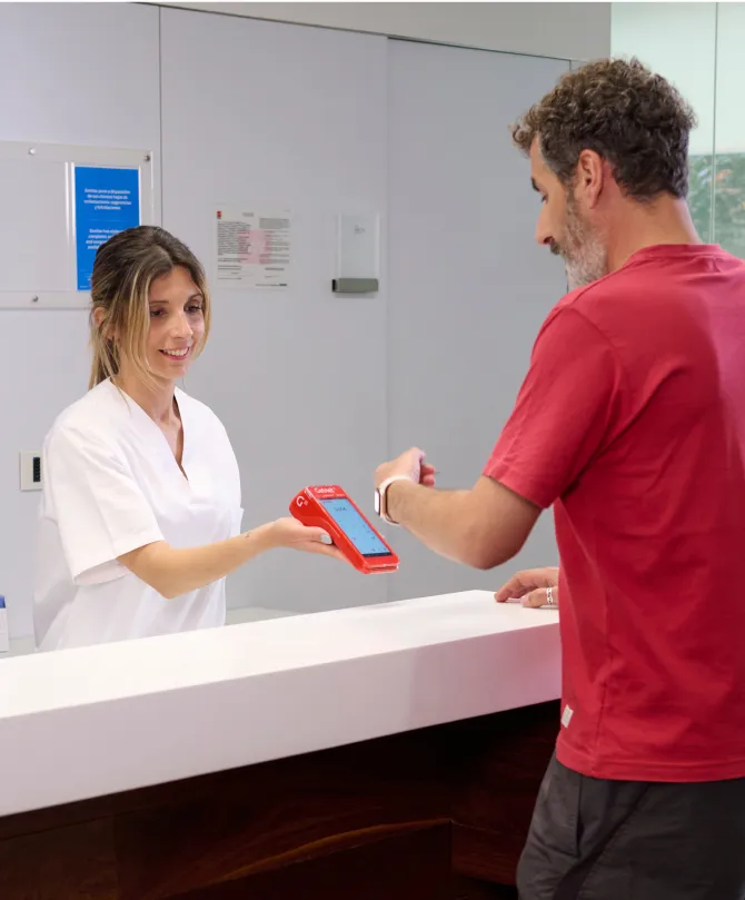 Persona pagando en una clínica con un reloj inteligente a un tpv getnet