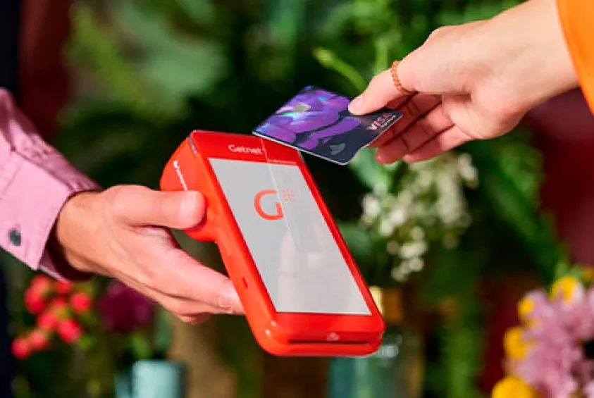 Persona pagando con una tarjeta de crédito en un datáfoto Getnet 