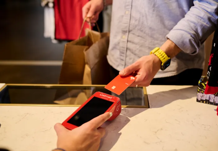 Persona pagando con una tarjeta de crédito en un datáfoto Getnet 
