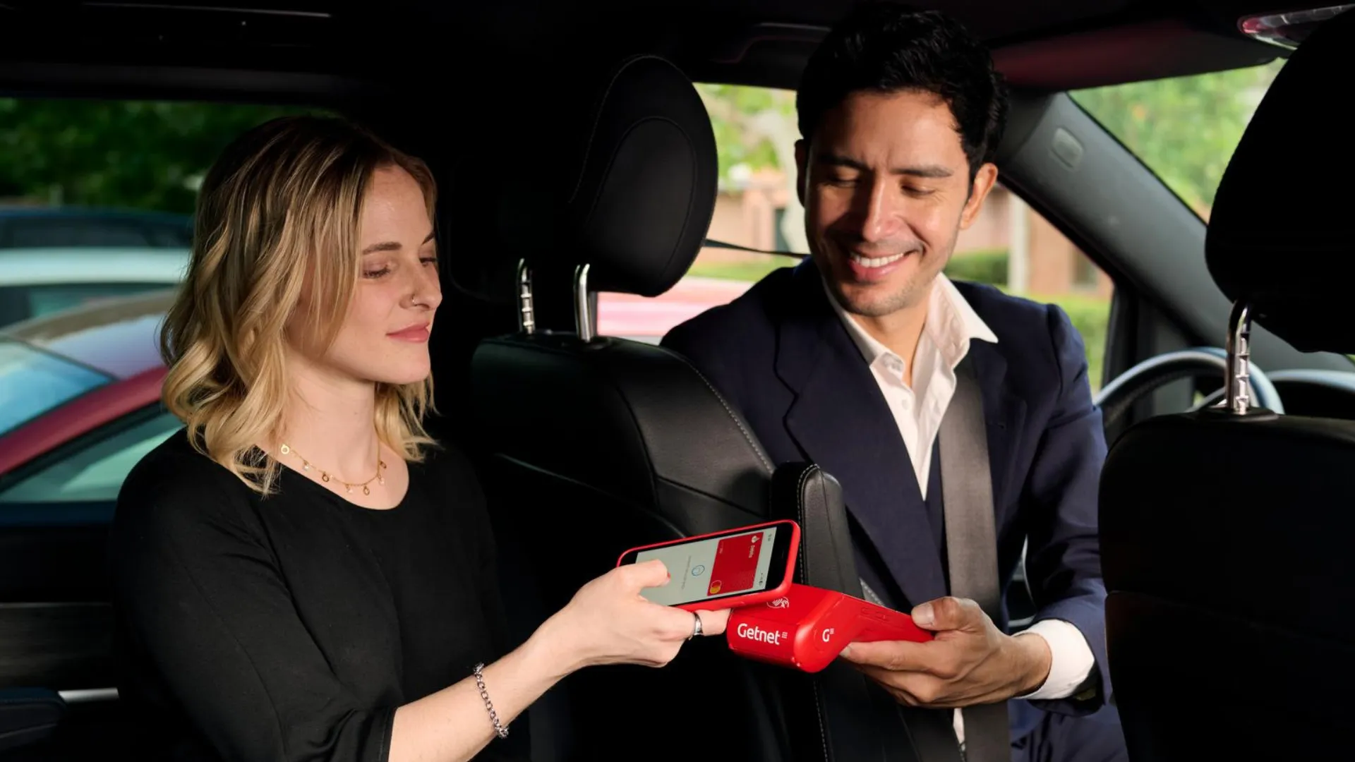 Persona pagando en un taxi con un tpv getnet usando un smartphone para pagar