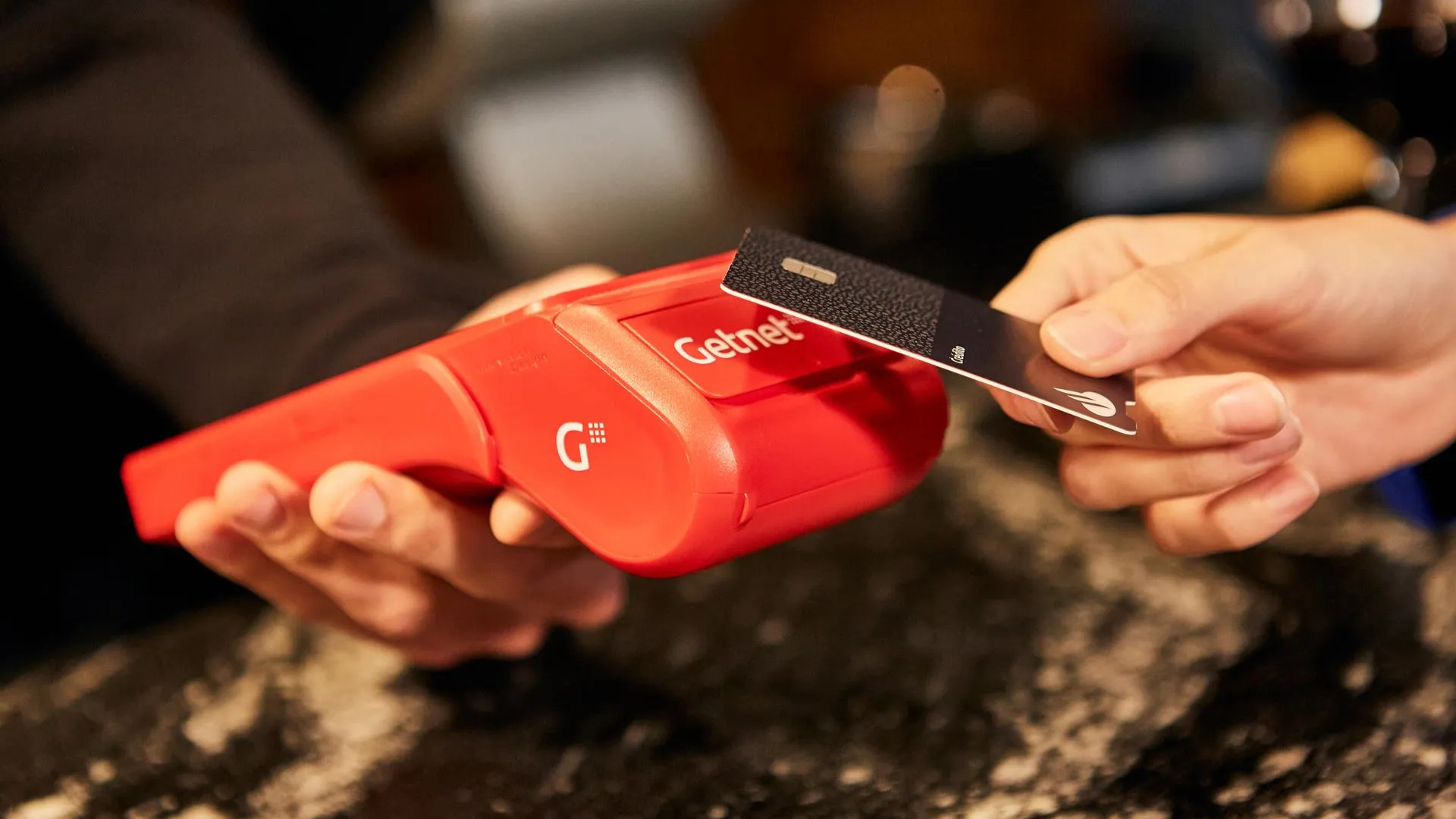 Persona pagando con una tarjeta de crédito en un datáfoto Getnet 