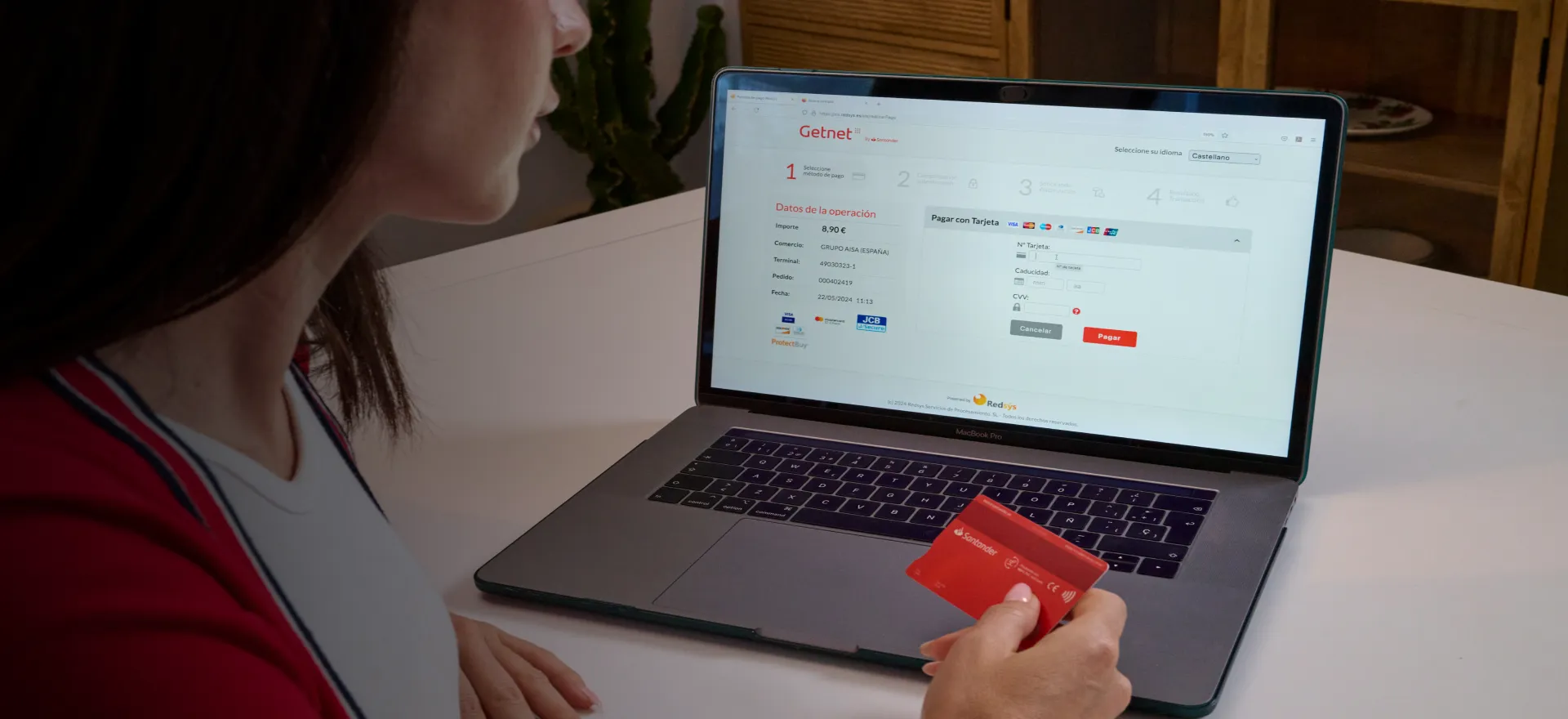 Persona sosteniendo una tarjeta de crédito con la que va a pagar online desde un ordenador portatil