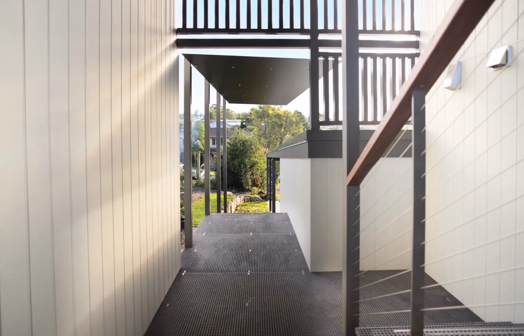 Elevated walkway between white walls with stairs 