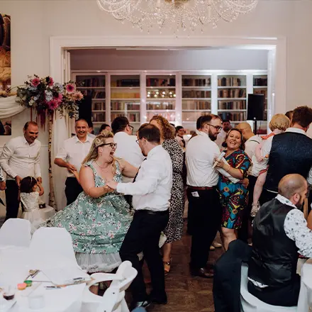 Fröhliche Gäste tanzen und feiern gemeinsam bei einer lebendigen Hochzeitsparty in elegant dekorierter Location.