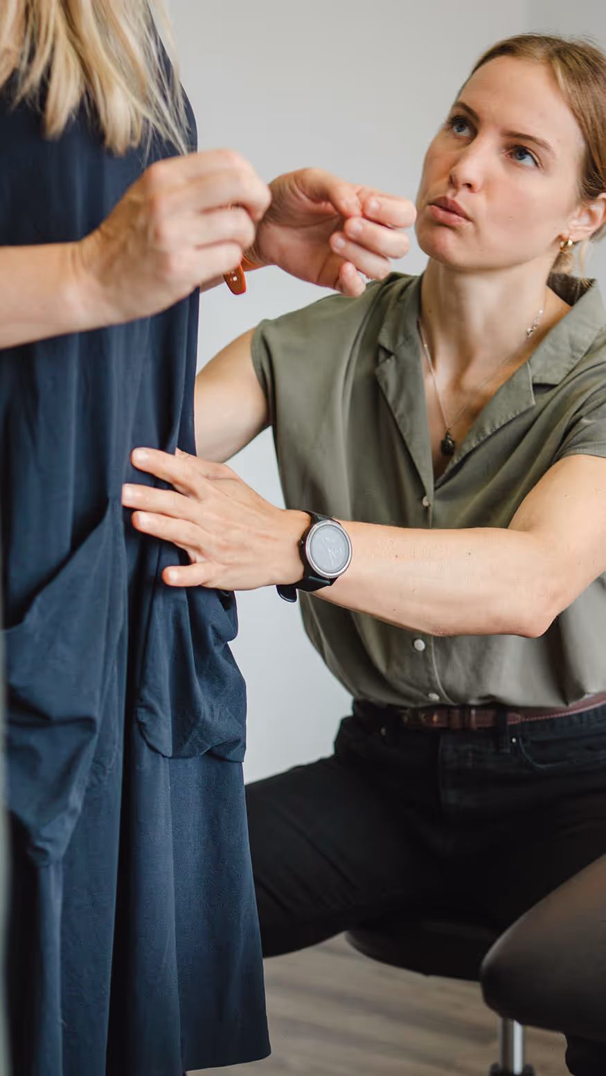 A woman correcting a colleague's posture to promote good back health in the office and proper working technique.