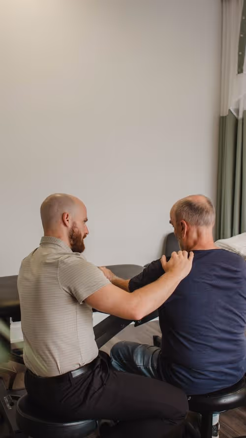 Un chiropraticien ajuste l'épaule d'un patient âgé dans un cadre clinique pour des options de traitement de soulagement de la douleur.