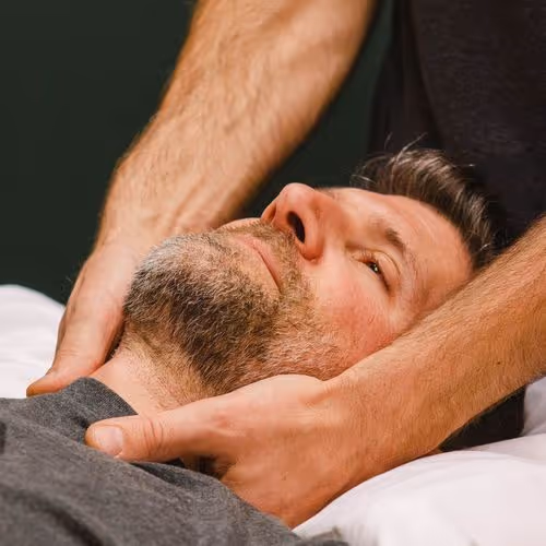 Un homme reçoit un massage relaxant sur le cou et le cuir chevelu sur une table.