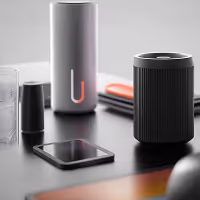 Modern tech gadgets including a smartphone, two cylindrical smart speakers, and a laptop on a desk.