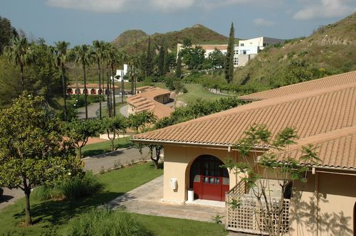 a building with a red door and a hill with trees and a road