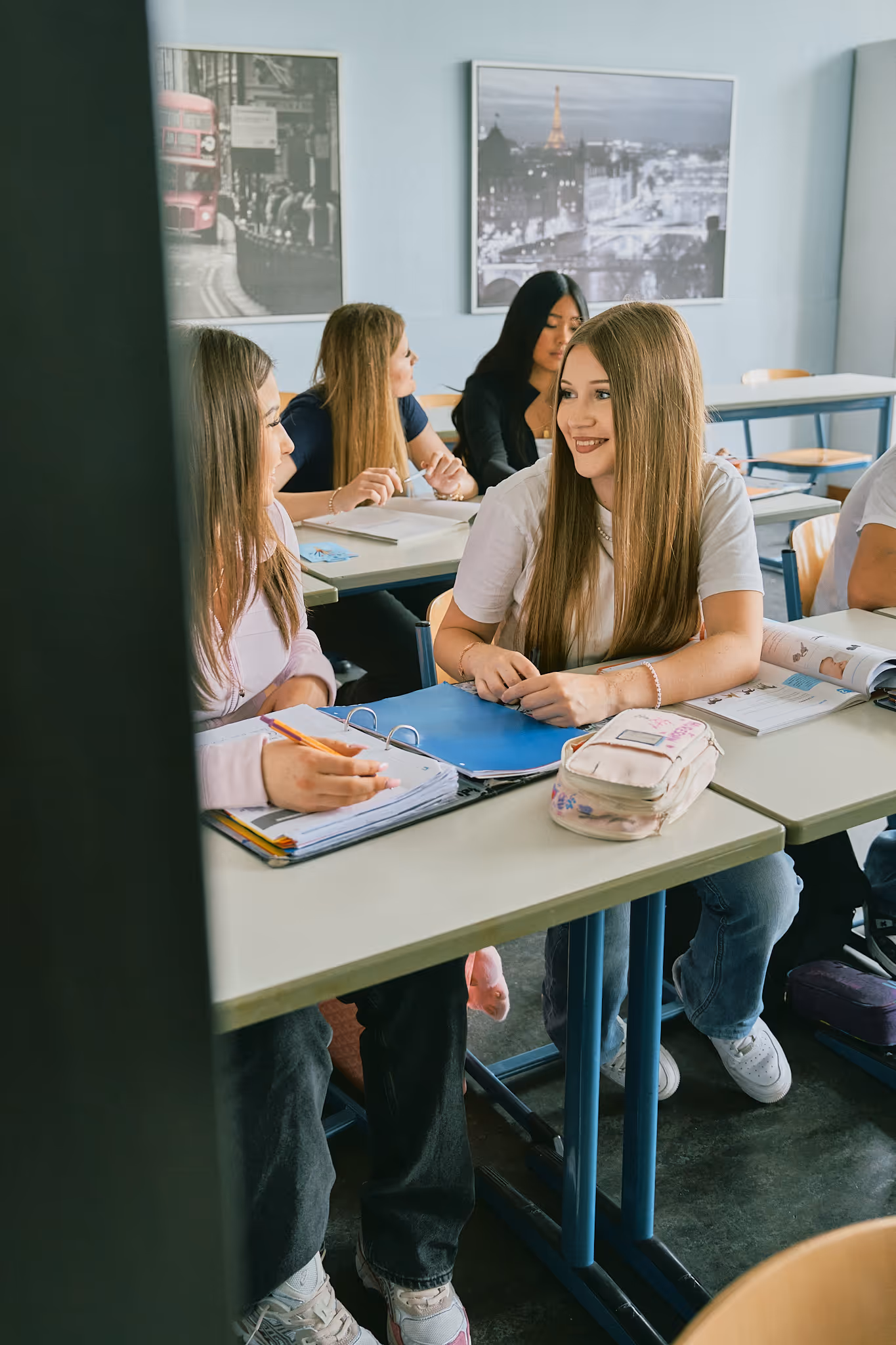 Schülerinnen lernen gemeinsam im Klassenzimmer mit Stadt-Postern