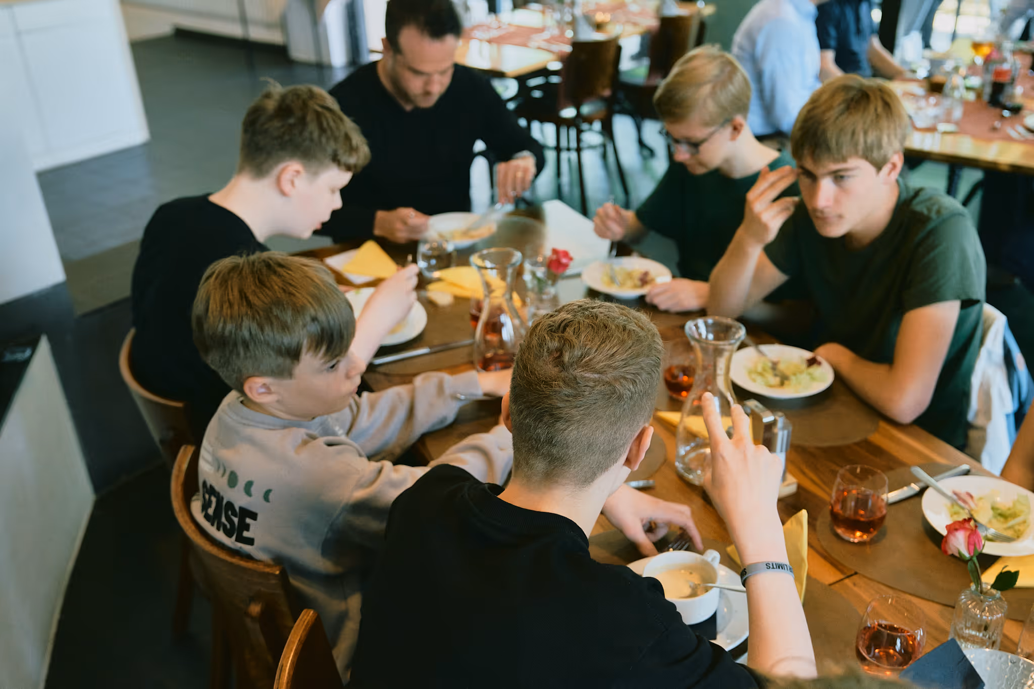 Jugendliche sitzen zusammen und essen an einem Holztisch in einem Café