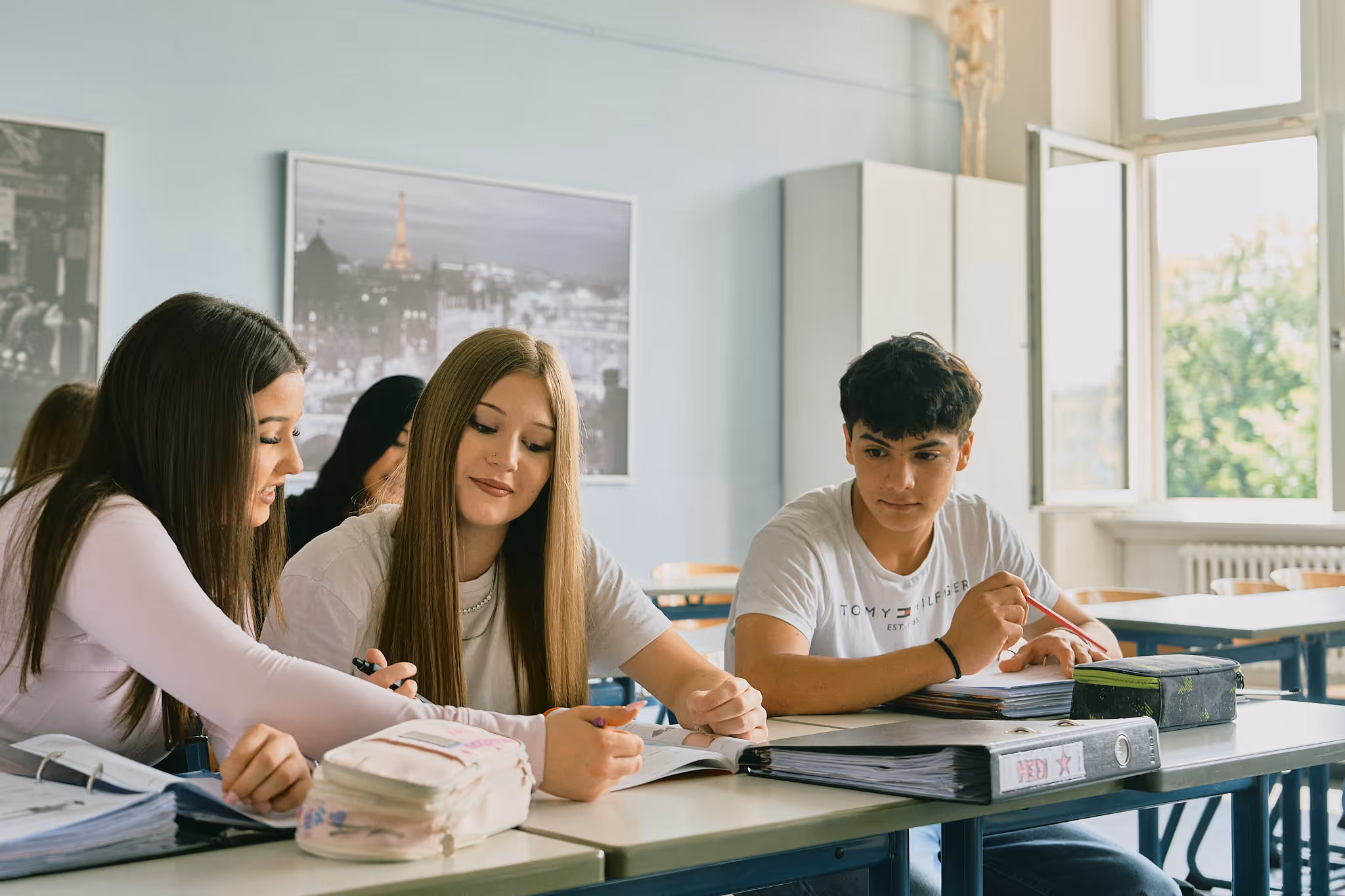 Schüler lernen gemeinsam im Klassenzimmer an Tischen mit Büchern