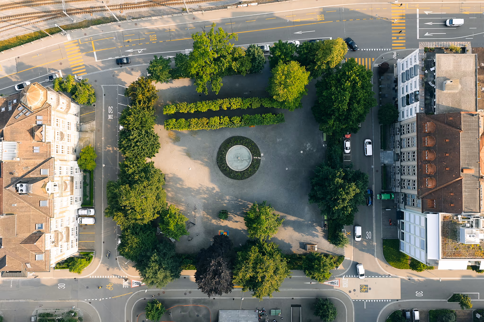 Luftaufnahme eines städtischen Platzes mit Bäumen und Kreisverkehr