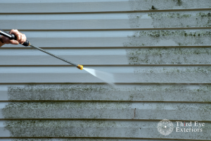 Powerwasher cleaning side of house