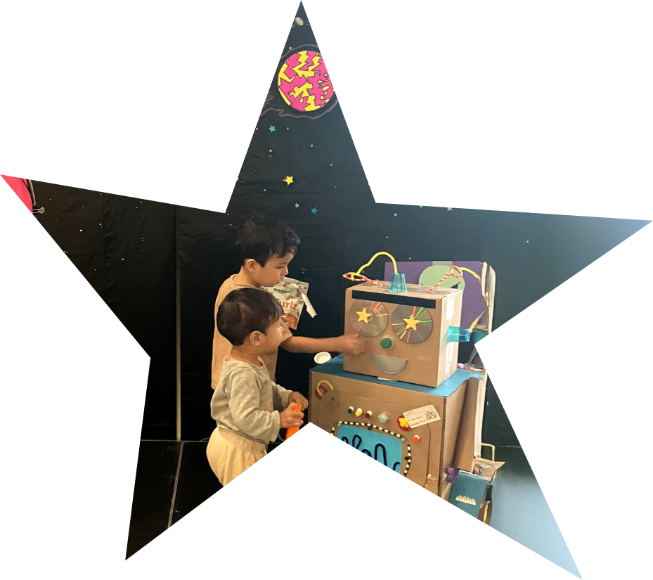 photo of 2 small skids playing with a cardboard robot