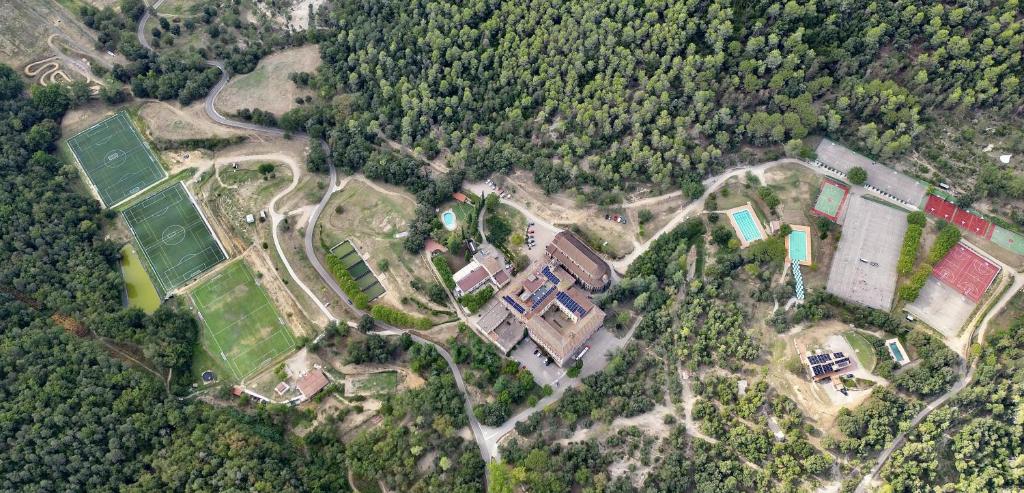 Vista aèria de la casa de colònies El Collell envoltada de natura, amb piscines, pistes esportives i edificis.