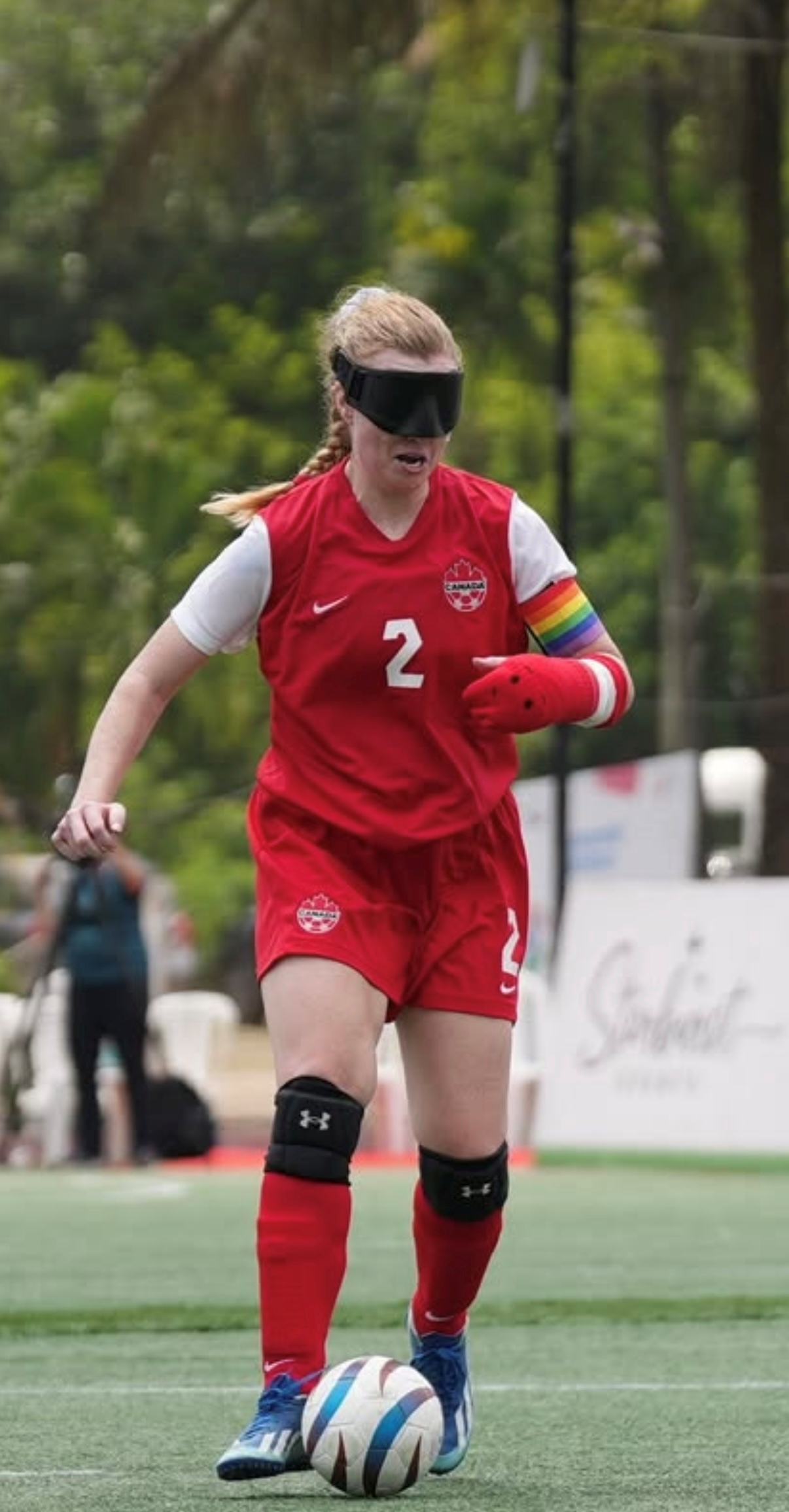 Team Captain Hillary in red uniform dribbles forward with her left arm in a cast.