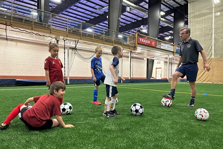 A white male in black track jacket speaks to a white female inh pink and black horizontal striped t-shirt. Both are smiling.