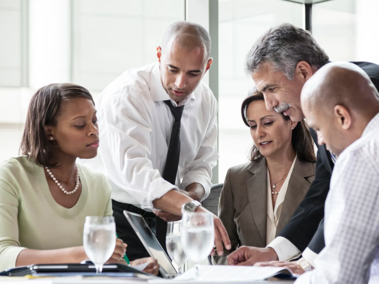A group of business professionals reviewing a laptop and documentation