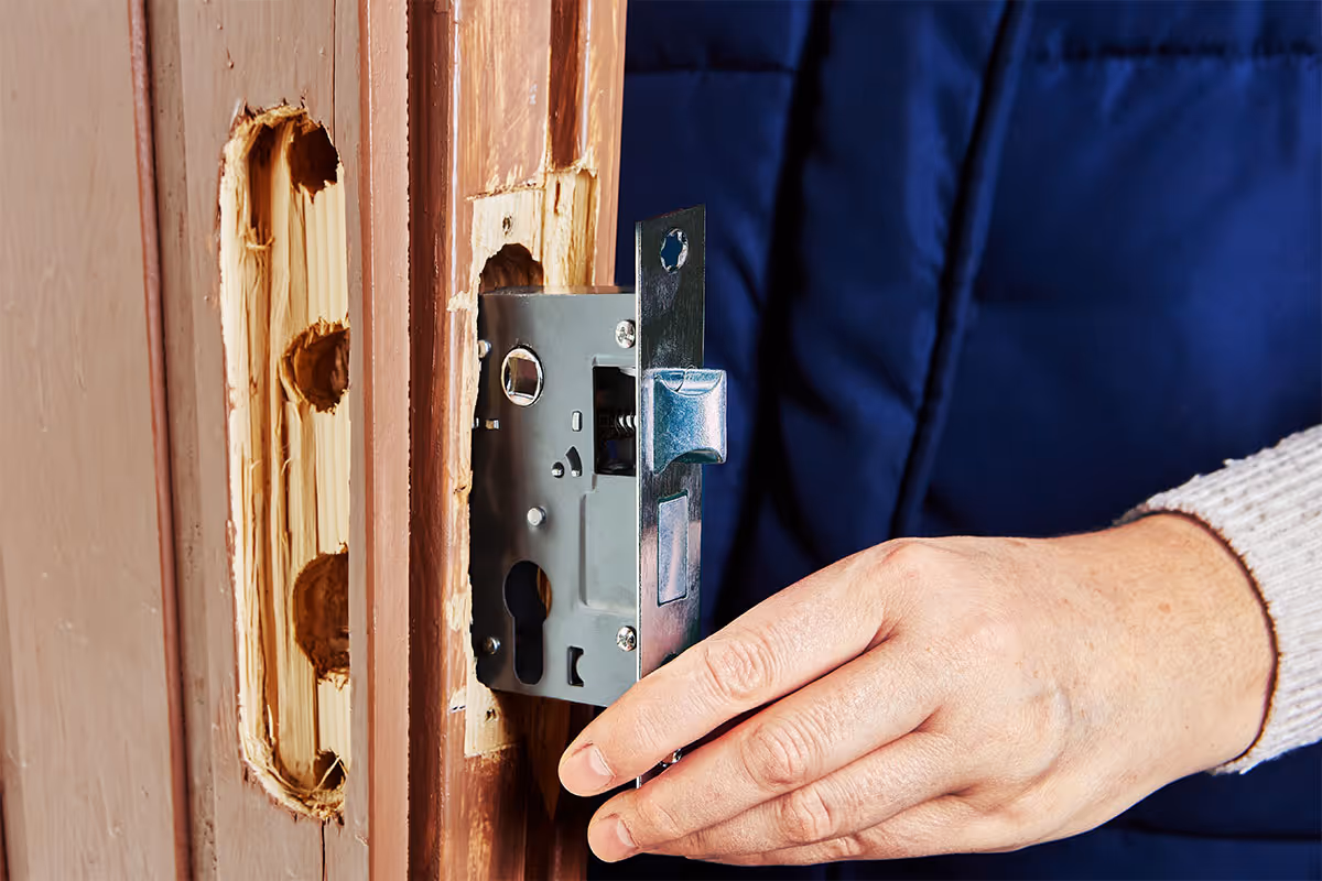 A locksmith replacing a home door lock.