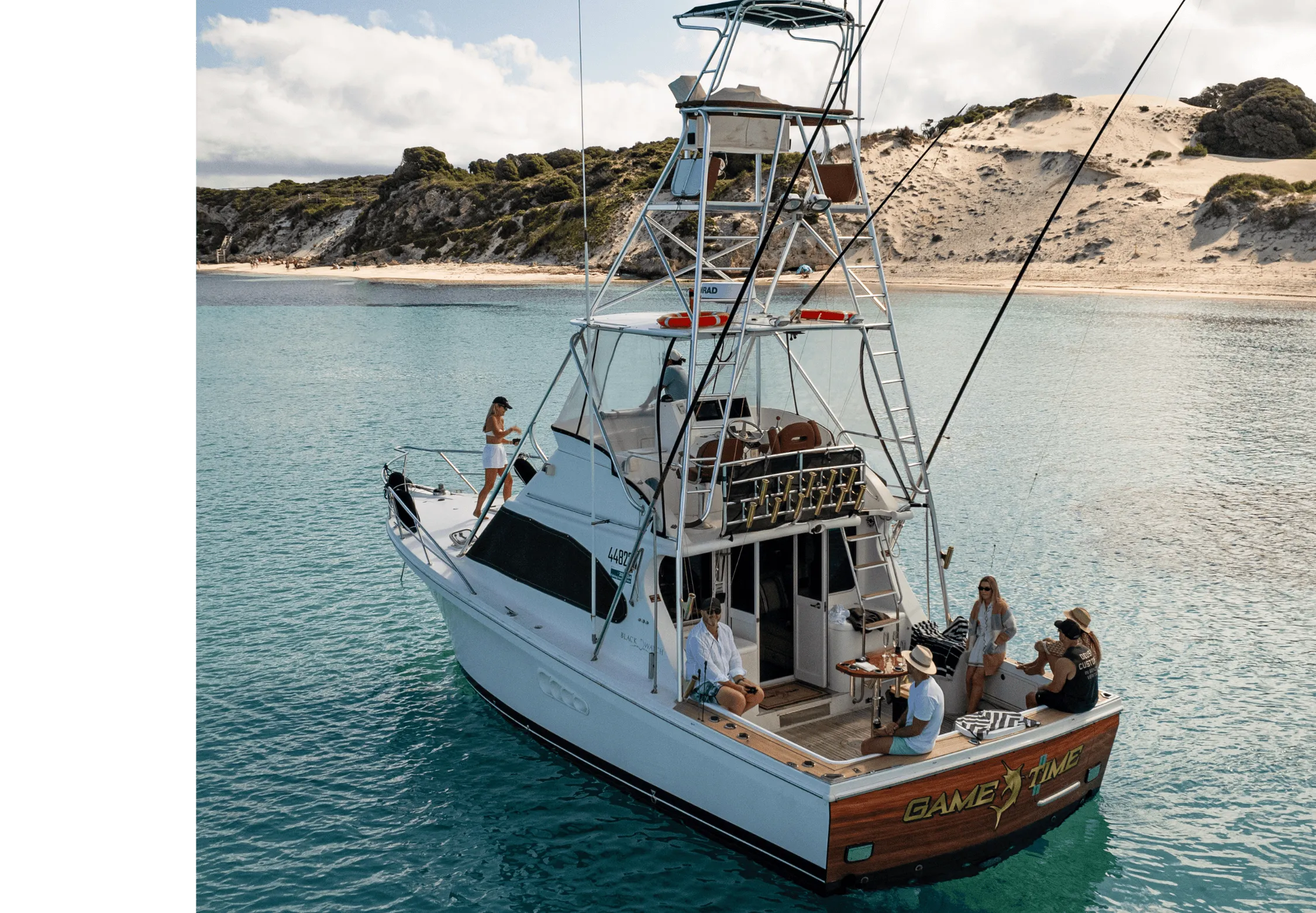 Game Time, a 40-foot Black Watch, anchored off a Rottnest Island beach with guests on the back deck