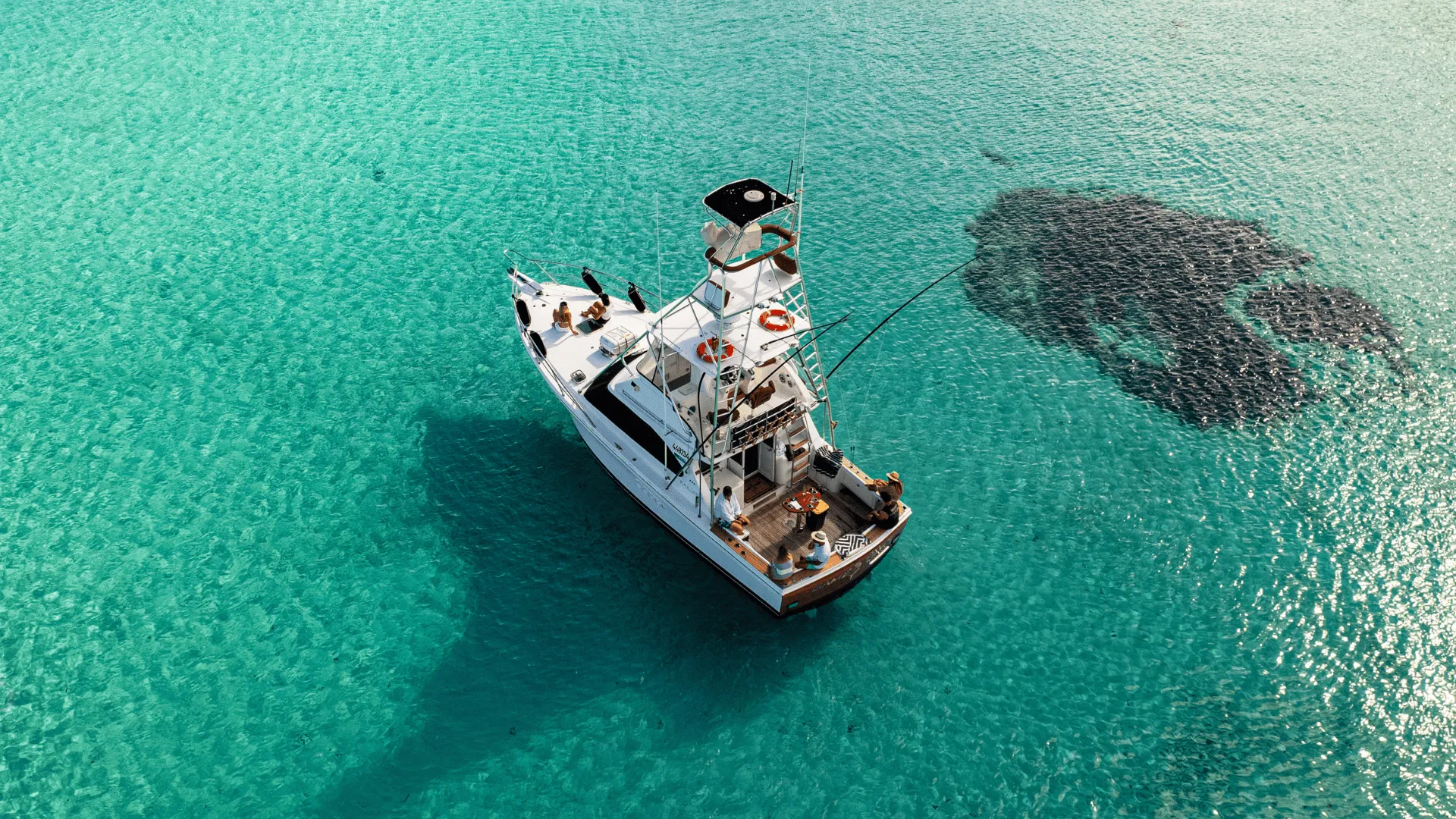 Game Time seen from above, anchored in a shallow turquoise bay