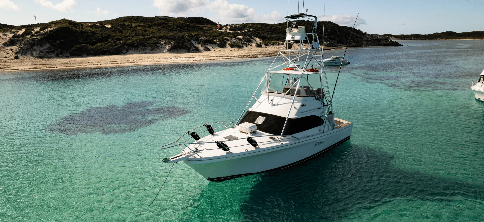Game Time at anchor in a Rottnest Island bay with the beach behind