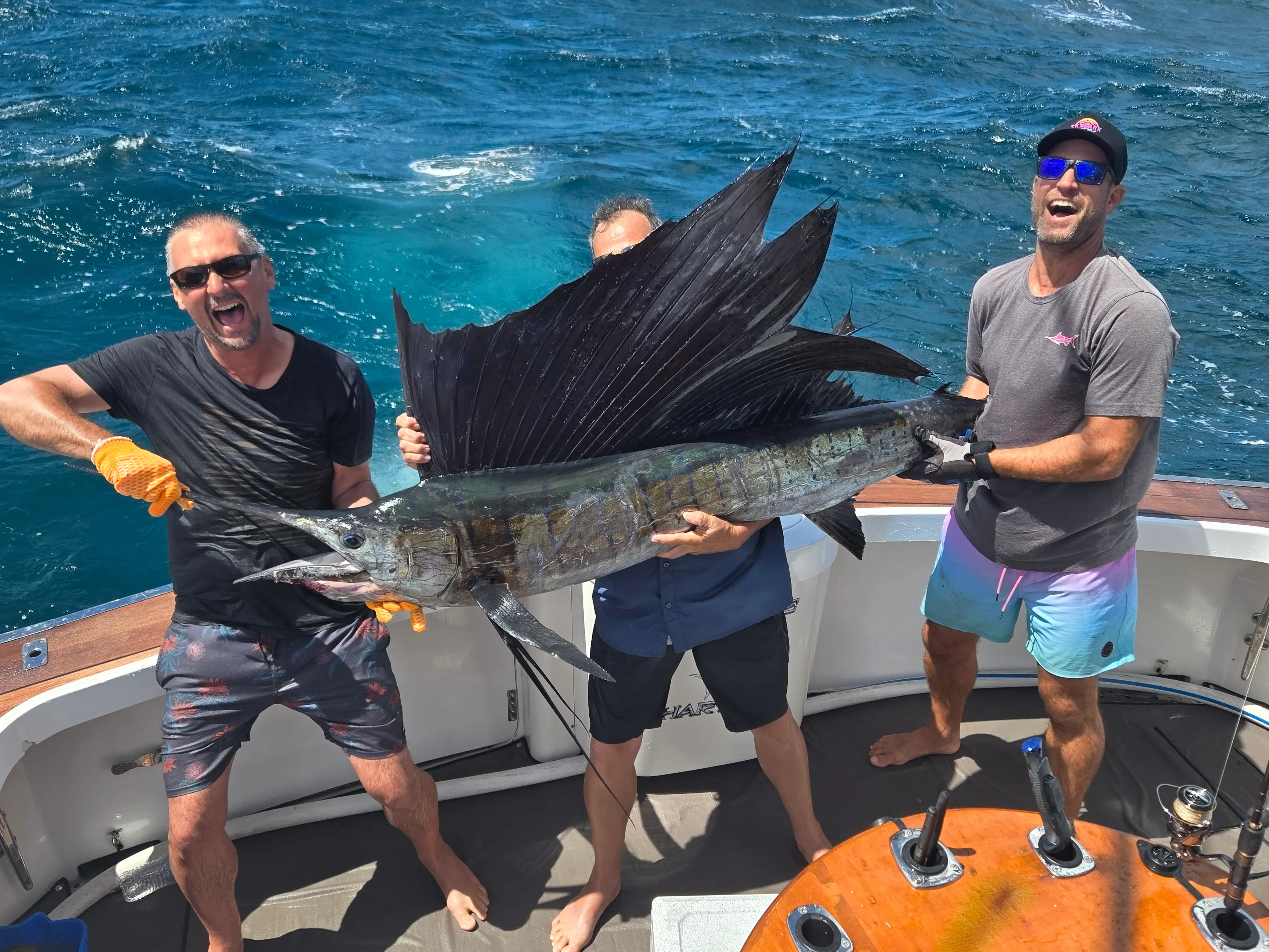 Three anglers holding a sailfish on deck before release with Game Time Charters