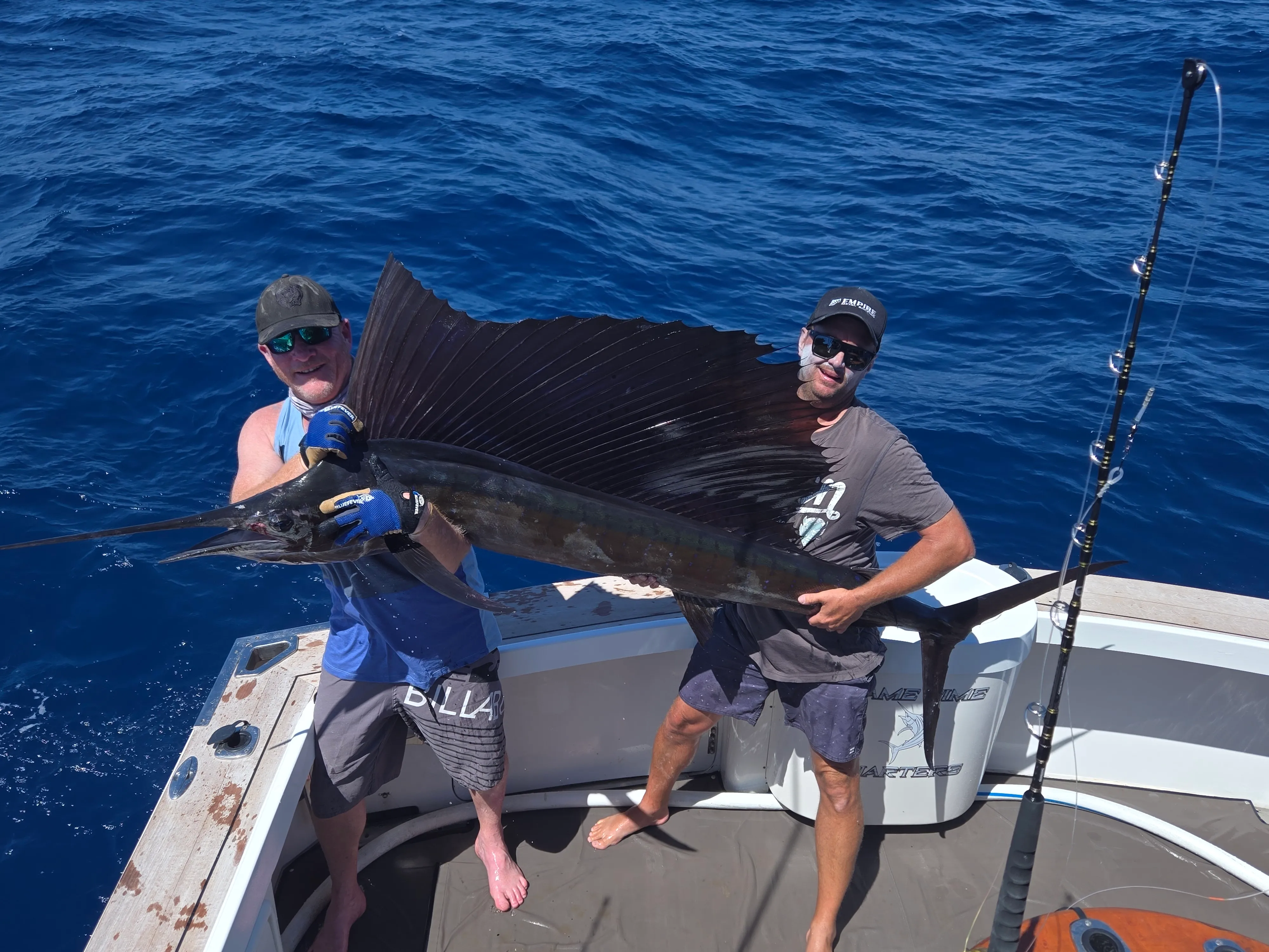 Two anglers holding a sailfish on deck before release with Game Time Charters