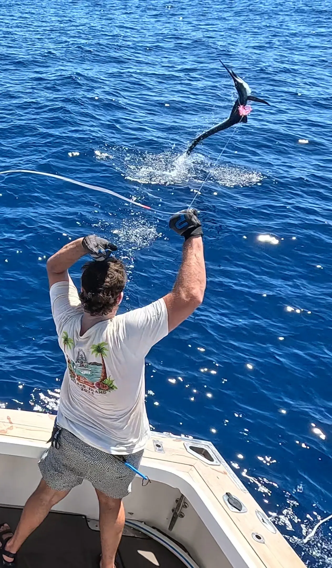 Angler celebrating as a billfish jumps behind the boat on a Game Time Charters charter