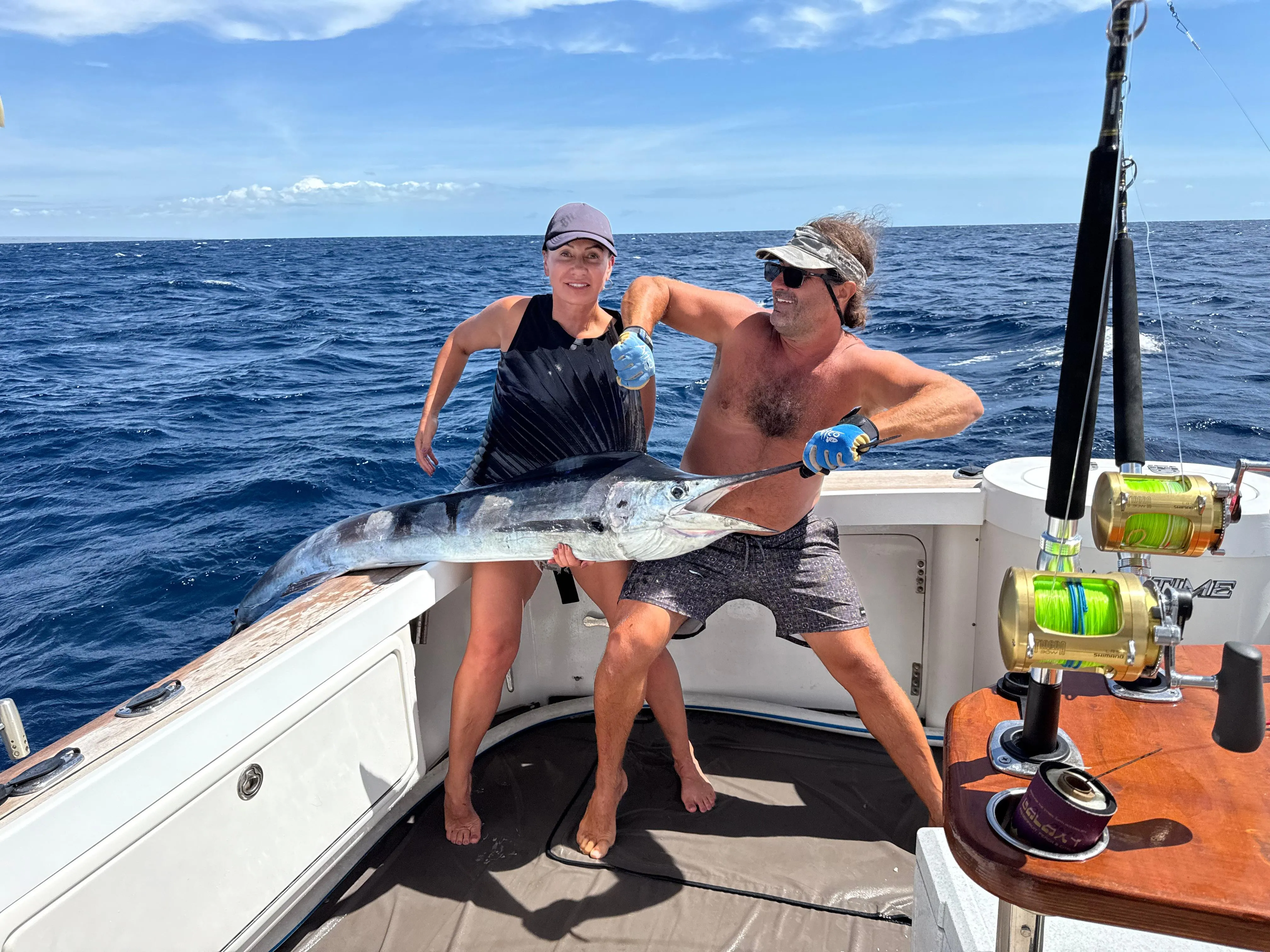 Two anglers with a sailfish at the covering board on a Game Time Charters charter