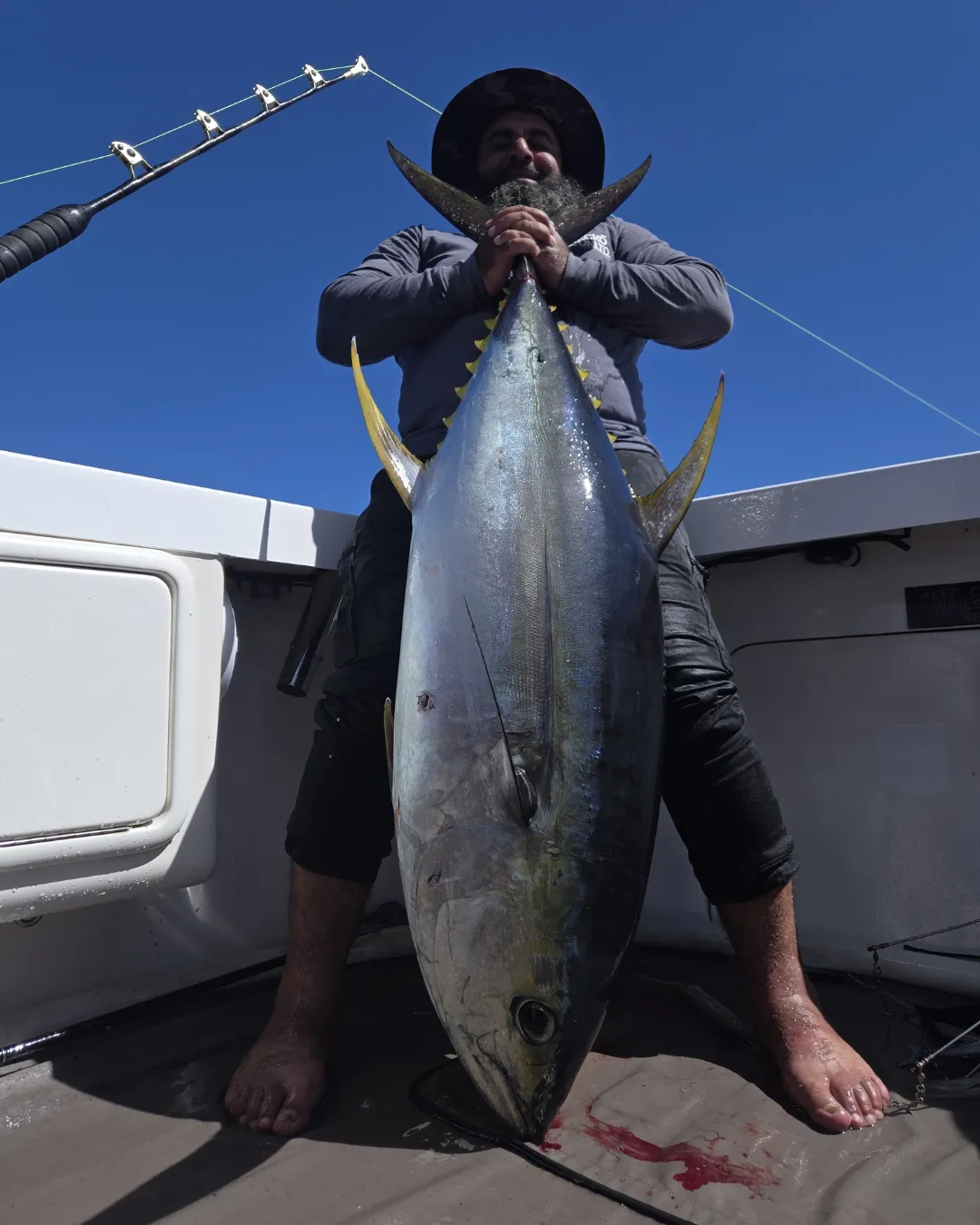 Angler standing behind a large yellowfin tuna on the deck with Game Time Charters