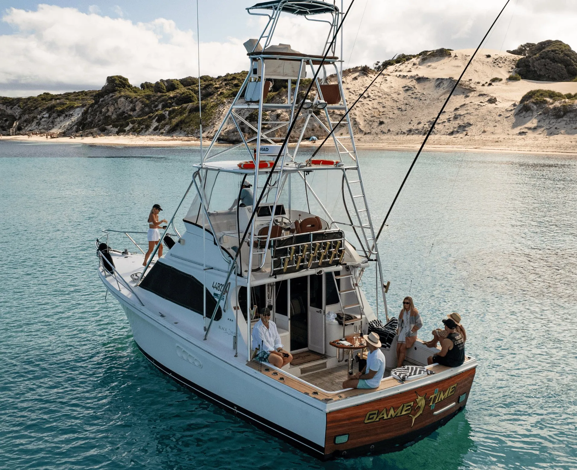 Game Time, a 40-foot Black Watch, anchored off a Rottnest Island beach with guests on the back deck
