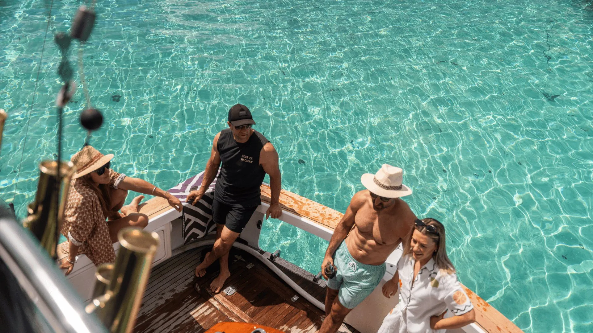 Four guests relaxing on the back deck of Game Time over clear turquoise water