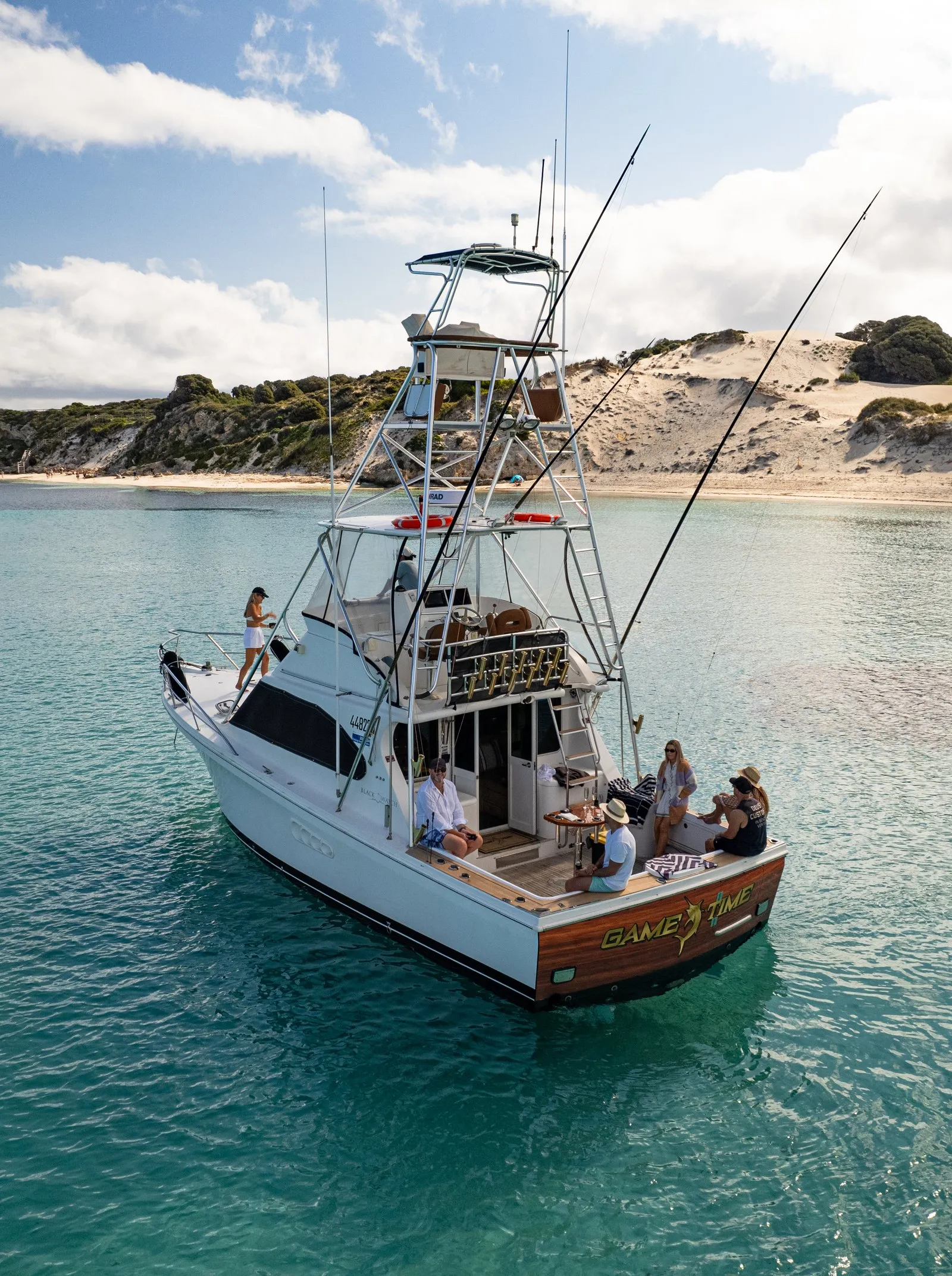 Game Time anchored under the dunes at Rottnest Island with guests on the back deck