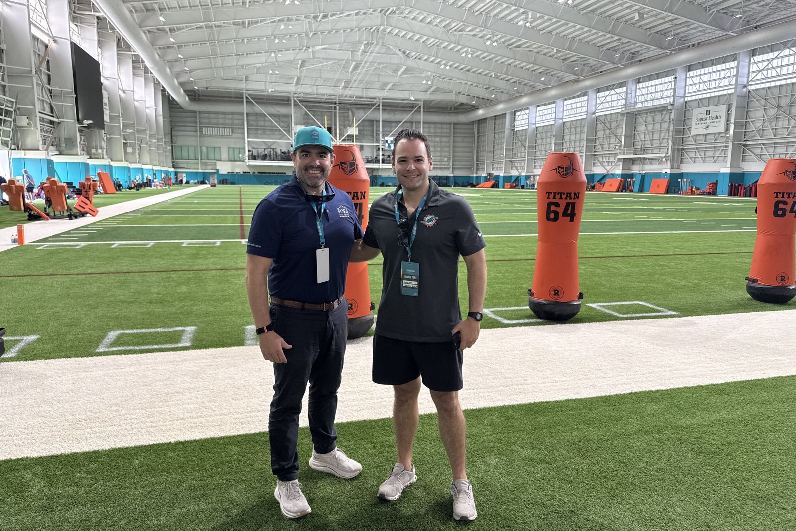 Jorge L. Fors, Jr. and Daniel C. Fors inside an indoor practice facility