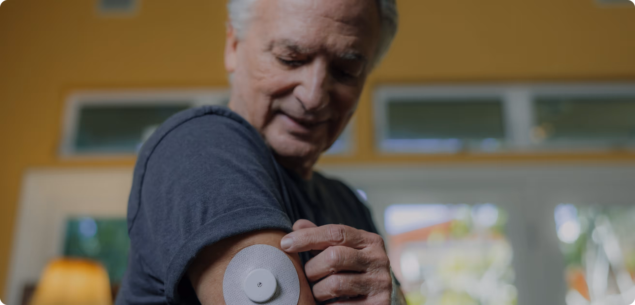 Person checking a medical sensor attached to their upper arm indoors.